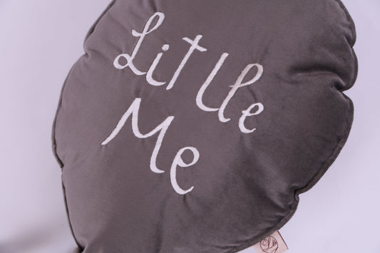 Round gray pillow with 'Little Me' text on a light purple background