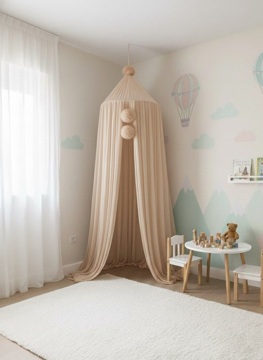 Children's room with a beige canopy, white chair, and small table with toys against a wall with mountain and cloud decorations.