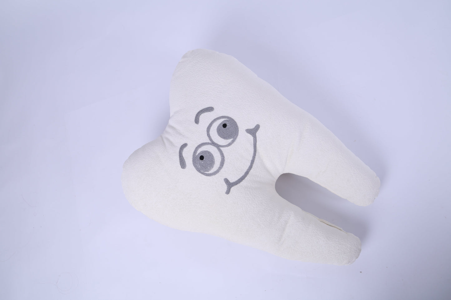 White neck pillow with cartoon face design on a light gray background