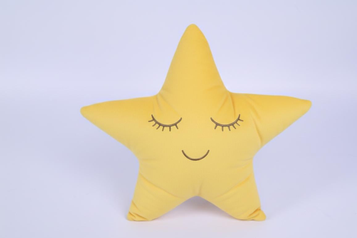 Yellow star-shaped pillow with a smiling face on a light purple background